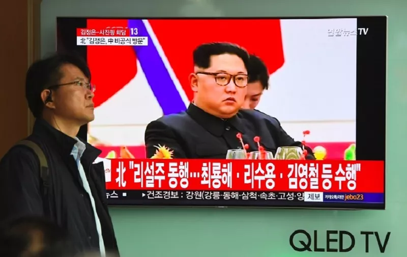 A man walks past a television news screen reporting about a visit to China by North Korean leader Kim Jong Un, at a railway station in Seoul on March 28, 2018.
North Korea's Kim Jong Un told Chinese President Xi Jinping that it was his "solemn duty" to make Beijing his first overseas destination and invited him to visit Pyongyang, the North's official news agency reported on March 28. / AFP PHOTO / Jung Yeon-je