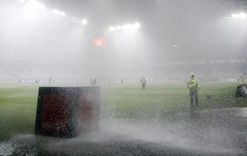 People protect themselves from a heavy shower as the French L1 football match Nice (OGC Nice) vs Nantes (FCN) is interrupted, on October 03, 2015 at the "Allianz Riviera" stadium in Nice, southeastern France.  AFP PHOTO / VALERY HACHE