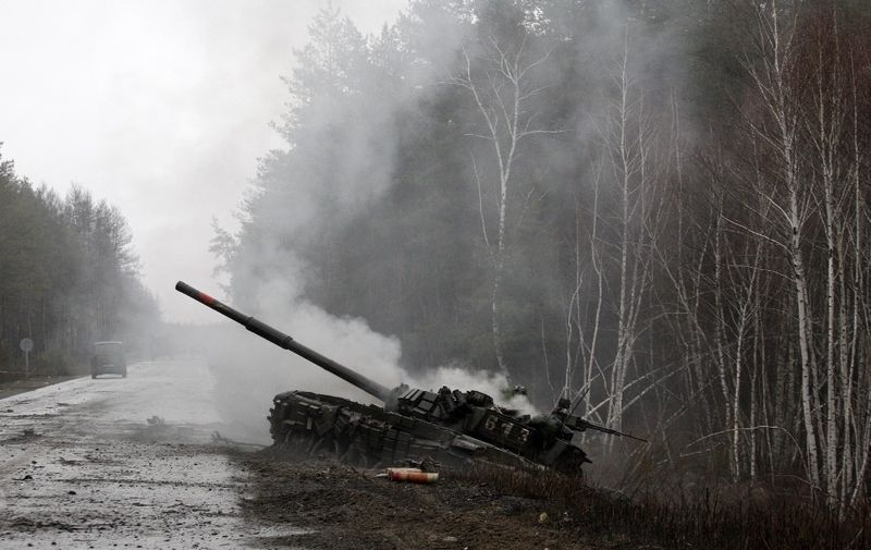 Smoke rises from a Russian tank destroyed by the Ukrainian forces on the side of a road in Lugansk region on February 26, 2022. - Russia on February 26 ordered its troops to advance in Ukraine "from all directions" as the Ukrainian capital Kyiv imposed a blanket curfew and officials reported 198 civilian deaths. (Photo by Anatolii Stepanov / AFP)