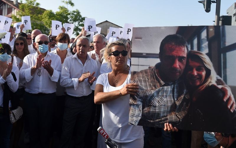 Veronique Monguillot, wife of bus driver Philippe Monguillot, declared brain dead after being attacked for refusing to let aboard a group of people who were not wearing face masks, holds a picture of her husband during a white march in Bayonne, southwestern France, on July 8, 2020. - Four men set upon 59-year-old Philippe Monguillot in the southwestern town of Bayonne on July 5 after he asked three of them to wear masks and tried to check another man's ticket. The other two men have been charged with non-assistance to a person in danger and one has also been charged with attempting to hide a suspect, the local prosecutor's office said. (Photo by GAIZKA IROZ / AFP)