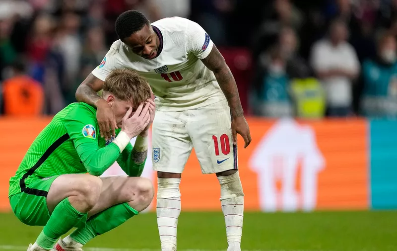 England's Raheem Sterling comforts England's goalkeeper Jordan Pickford after the penalty shootout of the Euro 2020 soccer championship final between England and Italy at Wembley stadium in London, Sunday, July 11, 2021. (AP Photo/Frank Augstein, Pool)
