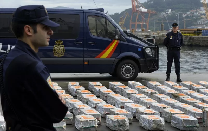 Policemen stand guard next to a part of seized drug packs on the vessel "riptide"at the port of Vigo, northwestern Spain, on June 13, 2013, Spanish police seized on May 31, 2013 a boat carrying three tonnes of cocaine in the Atlantic and arrested 21 people including the vessel's Korean captain and Indonesian crew.    AFP PHOTO/ MIGUEL RIOPA / AFP / MIGUEL RIOPA