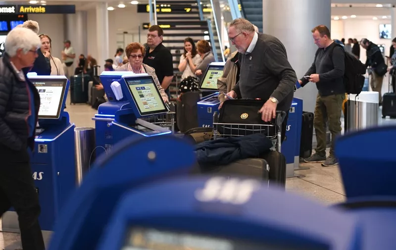 Travellers stand next to check-in counters during a strike of Scandinavian Airlines' (SAS) pilots to contest wages and working hours on April 26, 2019 at Copenhagen Airport in Kastrup. - Pilots at SAS walked off the job in Sweden, Denmark and Norway, stranding 70,000 travellers as more than 300 flights were cancelled, the airline said. Domestic, European and long-haul flights were all affected by the strike, it  said, predicting that a total of 170,000 passengers would be affected through April 28, 2019. (Photo by Philip Davali / Ritzau Scanpix / AFP) / Denmark OUT