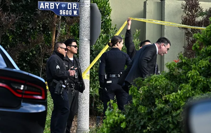 Police officers lift police tape for an investigator after an early morning shooting that left three people dead and four wounded in the Beverly Crest neighborhood of Los Angeles, just north of Beverly Hills, on January 28, 2023. Three people were shot dead January 28 and four others injured at a luxury home near Beverly Hills, at what US police described as a gathering at a short-term rental property. (Photo by Robyn BECK / AFP)