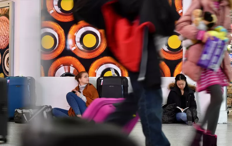 Passengers sit with their luggage in the South Terminal building at London Gatwick Airport, south of London, on December 21, 2018, as flights started to resume following the closing of the airfield due to a drones flying. - British police were Friday considering shooting down the drone that has grounded flights and caused chaos at London's Gatwick Airport, with passengers set to face a third day of disruption. Police said it was a "tactical option" after more than 50 sightings of the device near the airfield since Wednesday night when the runway was first closed. (Photo by Ben STANSALL / AFP)