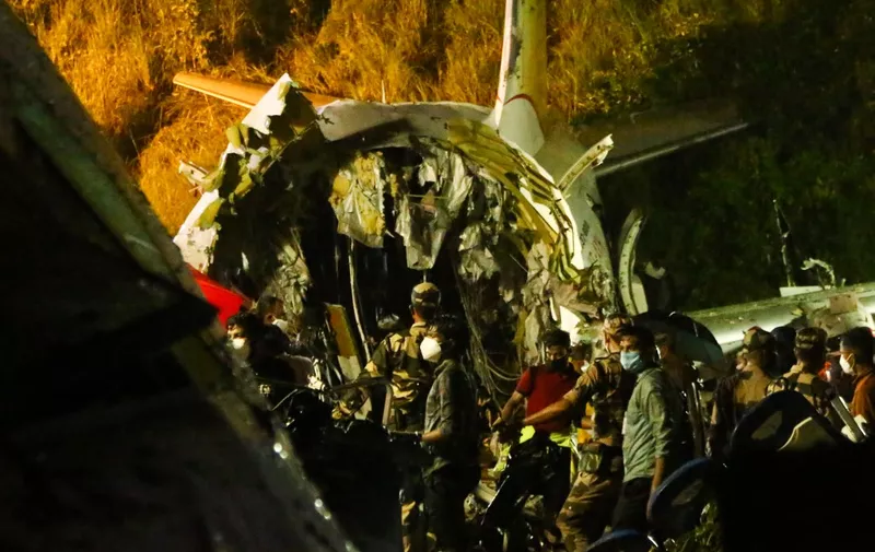 First responders inspect the wreckage of an Air India Express jet, which was carrying more than 190 passengers and crew from Dubai, after it crashed by overshooting the runway at Calicut International Airport in Karipur, Kerala, on August 7, 2020. - At least 14 people died and 15 others were critically injured when a passenger jet skidded off the runway after landing in heavy rain in India, police said on August 7. (Photo by Favas JALLA / AFP)