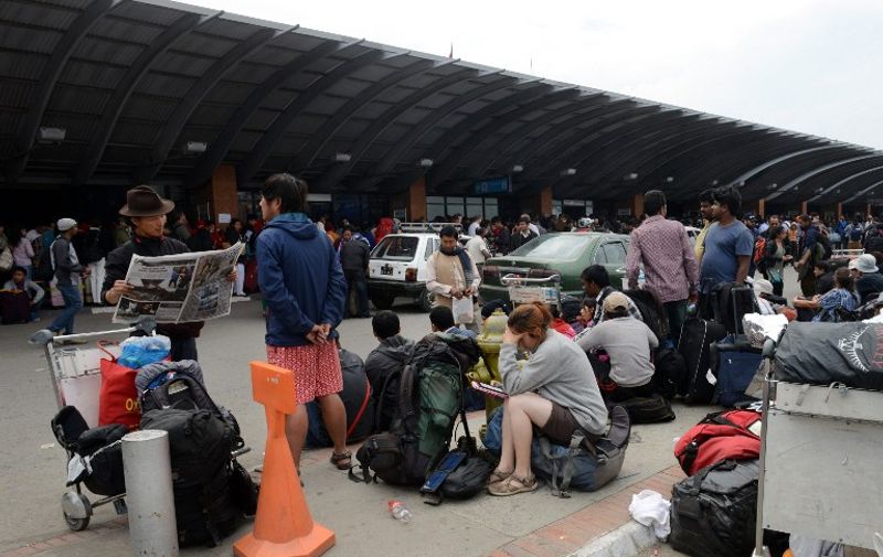 Travellers wait outside the departure hall of the airport in Kathmandu on April 26, 2015, as they wait to leave the Nepalese capital following a 7.8 earthquake which struck the Himalayan nation April 25.  Rescuers in Nepal searched frantically for survivors of a quake that killed more than 2,000, digging through rubble in the devastated capital Kathmandu and airlifting victims of an avalanche at Everest base camp.  AFP PHOTO / PRAKASH MATHEMA