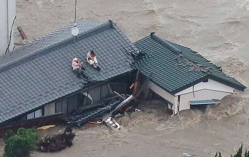 Local residents wait to be rescued on the roof of their home in a flooded area in Joso, Ibaraki Prefecture, on September 10, 2015. The Japanese city 50 km north east of Tokyo was flooded when Kinugawa river burst its banks, destroying homes and cars as desperate residents waited for help, and as thousands of people were ordered to evacuate. AFP PHOTO/Jiji Press      JAPAN OUT