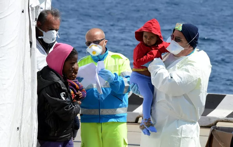 Italian Red Cross operators give first aid to immigrants as they arrive on April 15, 2015 in the Italian port of Messina in Sicily. Italian coastguards intercepted 42 boats on April 12 and 13, carrying 6,500 migrants attempting to make the hazardous crossing to Europe. AFP PHOTO / GIOVANNI ISOLINO