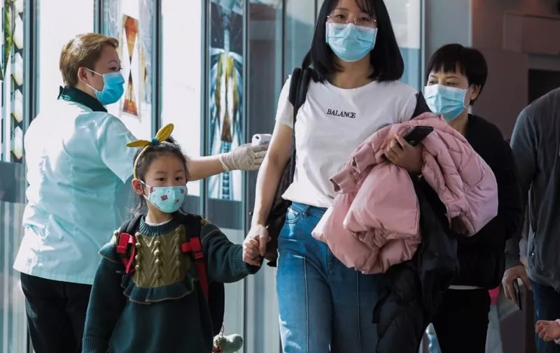 A health officer (L) screens arriving passengers from China at Changi International airport in Singapore on January 22, 2020 as authorities increased measure against coronavirus. (Photo by ROSLAN RAHMAN / AFP)