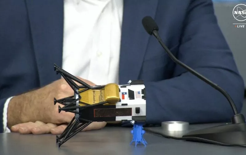 This frame grab from Nasa, shows Intuitive Machines CEO Steve Altemus holding a model of Odysseus to show its position on the side during a press conference at Johnson Space Center in Houston, Texas on February 23, 2024. The first American spaceship on the Moon since Apollo probably face-planted into the dirt after catching on a rock during its dramatic landing, the company that built it said Friday. (Photo by Handout / NASA TV / AFP)
