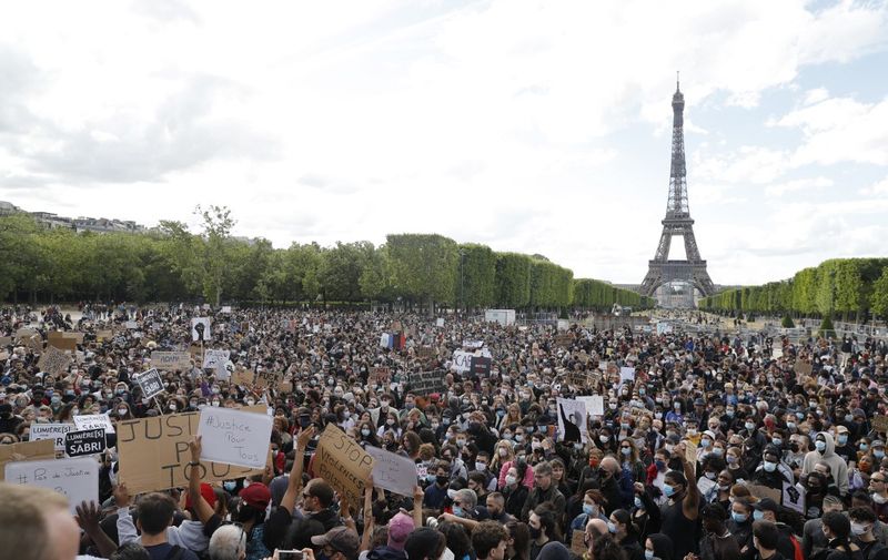 A protester holds a banner on Champ de Mars, in Paris on June 6, 2020, as part of 'Black Lives Matter' worldwide protests against racism and police brutality in the wake of the death of George Floyd, an unarmed black man killed while apprehended by police in Minneapolis, US. - Police banned the rally as well as a similar second one on the Champ de Mars park facing the Eiffel Tower today, saying the events were organised via social networks without official notice or consultation. But on June 2, another banned rally in Paris drew more than 20000 people in support of the family of Adama Traore, a young black man who died in police custody in 2016. (Photo by GEOFFROY VAN DER HASSELT / AFP)