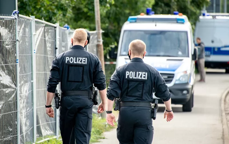Policemen walk past their vehicles during a search in a garden allotment in the northern German city of Hanover on July 29, 2020, in connection with the disappearance of British girl Madeleine McCann. - Police revealed in June 2020 that they were investigating a 43-year-old German man over the 2007 disappearance of three-year-old "Maddie", saying they believe he killed her. Madeleine went missing from her family's holiday apartment in the Portuguese holiday resort of Praia da Luz on May 3, 2007, a few days before her fourth birthday, as her parents dined with friends at a nearby tapas bar. (Photo by Hauke-Christian Dittrich / AFP)