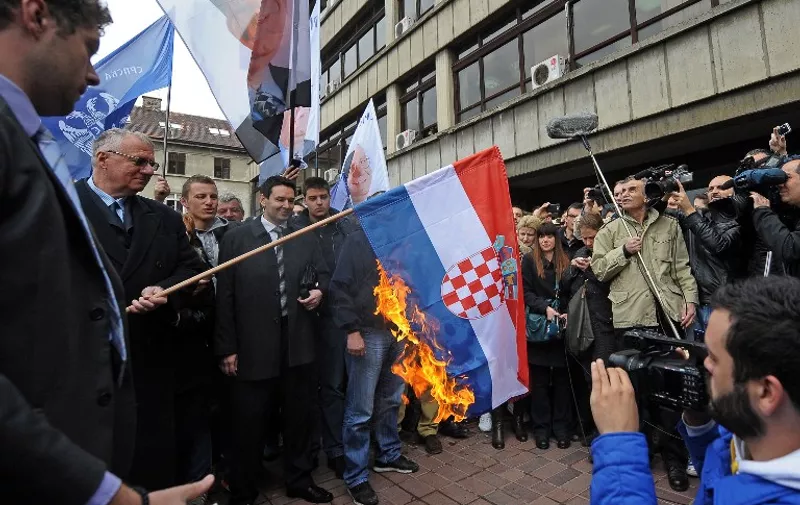 Serbian nationalist politician Vojislav Seselj (2nd L) surrounded by his supporters burns a Croatian flag on April 1, 2015 outside a tribunal in Belgrade. Alleged Serbian war crimes suspect Seselj set fire to the flag in a deliberate act of defiance after he was ordered to return to his detention cell in The Hague. Seselj said burning the flag was his answer to Croatia's leaders, who have welcomed the March 31 order by a UN court revoking his provisional release.  
                   AFP PHOTO / ALEXA STANKOVIC / AFP / ALEXA STANKOVIC