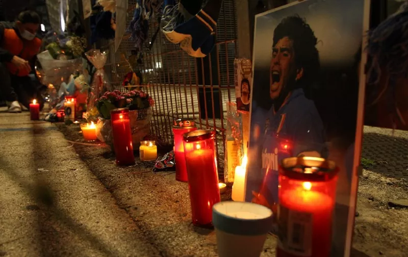 A view shows a makeshift shrine set up at the main entrance of the San Paolo stadium in Naples on November 25, 2020 with an image of Argentinian football legend Diego Maradona, as people gather to mourn after the annoucement's of Maradona's death. - Argentine football legend Diego Maradona has died at the age of 60, his spokesman announced November 25, 2020. (Photo by CARLO HERMANN / AFP)