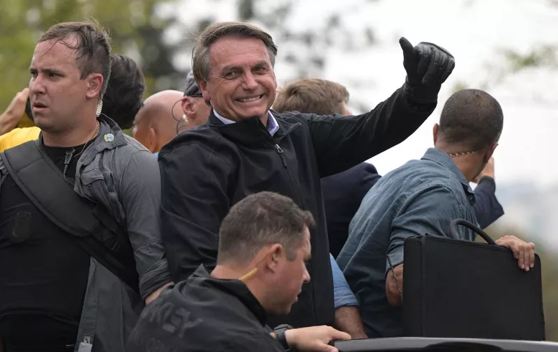 Brazilian president and re-election candidate Jair Bolsonaro gestures during a motorcade on the eve of the presidential election, in Sao Paulo, Brazil, on October 1, 2022. - Brazilians go to the polls Sunday in South America's biggest economy, plagued by gaping inequalities and violence, where voters ar expected to choose between far-right incumbent Jair Bolsonaro and leftist front-runner Luiz Inacio Lula da Silva, any of which must garner 50 percent of valid votes, plus one, to win in the first round. (Photo by ERNESTO BENAVIDES / AFP)