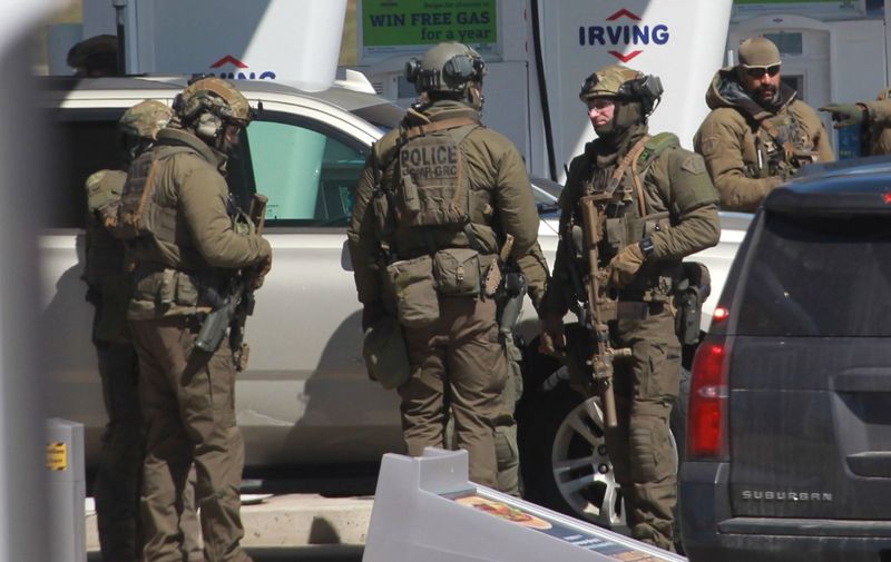 Members of the Royal Canadian Mounted Police (RCMP) tactical unit confer after the suspect in a deadly shooting rampage was neutralized at the Big Stop near Elmsdale, Nova Scotia, Canada, on April 19, 2020. - A gunman killed at least 10 people in an overnight shooting rampage across rural Nova Scotia, before being found dead following an hours-long manhunt, Canadian federal police said April 19. Earlier identified as 51-year-old Gabriel Wortman, the suspect had been on the run since Saturday night, when police were alerted to shots being fired in the small community of Portapique, around 100 kilometers (60 miles) from Halifax, capital of the Atlantic province. (Photo by tim krochak / AFP)