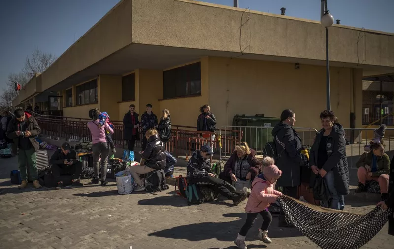 Ukrainian evacuees stand outside the train station in Przemysl, near the Polish-Ukrainian border, on March 22, 2022, following Russia's military invasion launched on Ukraine. - The UN says almost 3,6 million people have fled Ukraine since the Russian invasion, with more than two million of them heading to neighbouring Poland. (Photo by Angelos Tzortzinis / AFP)