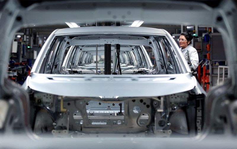 An employee of German car maker Volkswagen (VW) works on an assembly line to produce models of the Volkswagen ID.3 electric car at the Volkswagen car factory in Zwickau, eastern Germany, on February 25, 2020. (Photo by RONNY HARTMANN / AFP)