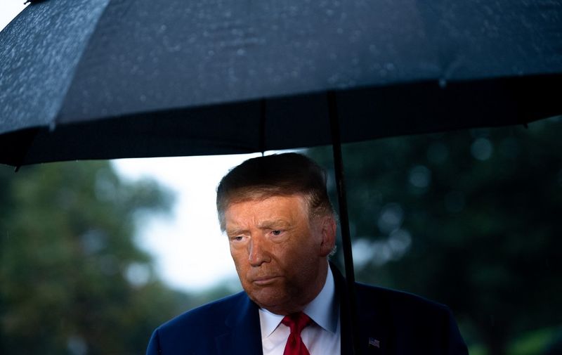 US President Donald Trump holds an umbrella as he speaks to the media under the rain prior to departing from the South Lawn of the White House in Washington, DC, September 17, 2020, as he travels to a campaign event in Wisconsin. (Photo by SAUL LOEB / AFP)
