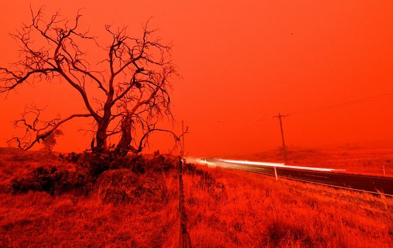 A long exposure picture shows a car commuting on a road as the sky turns red from smoke of the Snowy Valley bushfire on the outskirts of Cooma on January 4, 2020. - Up to 3,000 military reservists were called up to tackle Australia's relentless bushfire crisis on January 4, as tens of thousands of residents fled their homes amid catastrophic conditions. (Photo by SAEED KHAN / AFP)