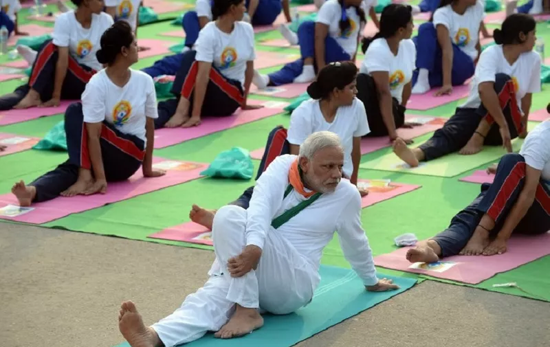 Indian Prime Minister Narendra Modi (C) participates in a mass yoga session along with other Indian yoga practitioners to mark the International Yoga Day on Rajpath in New Delhi on June 21, 2015.  Prime Minister Narendra Modi on June 21 hailed the first International Yoga Day as a "new era of peace", moments before he took to a mat and joined thousands in the heart of New Delhi to celebrate the ancient Indian practice.  AFP PHOTO / PRAKASH SINGH