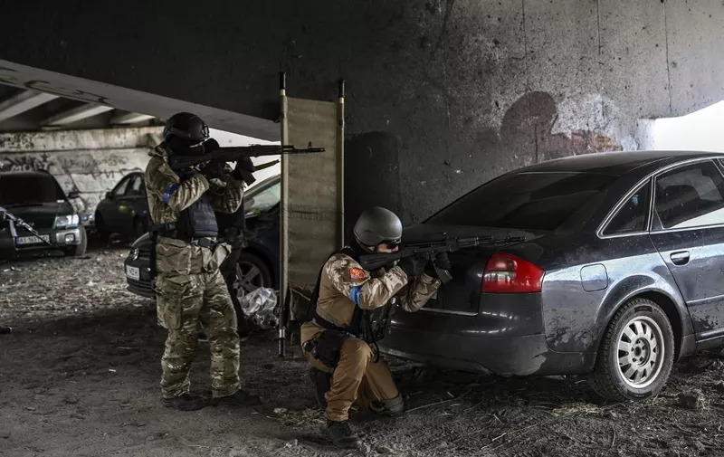 Ukrainian servicemen aim with their weapons at a moving car from a postition under a destroyed bridge in the city of Irpin, northwest of Kyiv, on March 13, 2022. - Russian forces advance ever closer to the capital from the north, west and northeast. Russian strikes also destroy an airport in the town of Vasylkiv, south of Kyiv. A US journalist was shot dead and another wounded in Irpin, a frontline northwest suburb of Kyiv, medics and witnesses told AFP. (Photo by Aris Messinis / AFP)