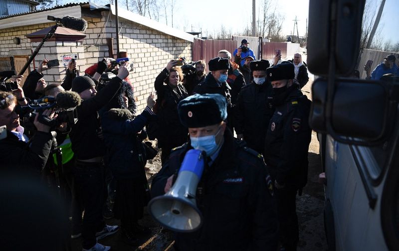 A police officer uses a loudspeaker asking journalists to leave following the detention of Russian opposition leader Alexei Navalny's lawyers Olga Mikhailova and Vadim Kobzev after they gathered with the media on a road and, according to police, were disturbing the traffic, outside the IK-2 prison colony in the town of Pokrov in Vladimir Region on March 22, 2022. - A Russian court on March 22 sentenced jailed Kremlin critic Alexei Navalny to nine years in prison after he was found guilty of embezzlement and contempt of court, an AFP journalist said. (Photo by AFP)