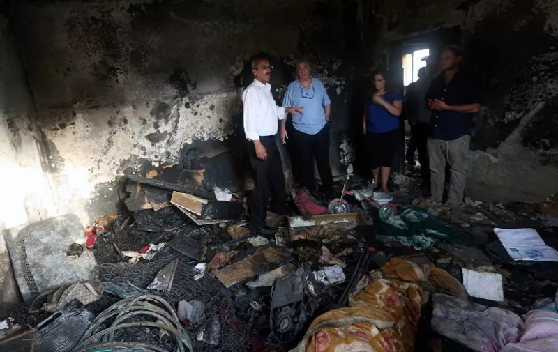 Israeli peace activists stand in the Dawabsha family's home set on fire by suspected Jewish extremists and where a Palestinian toddler was burned to death earlier in the week, on August 2, 2015 in the West Bank village of Duma. The firebombing of the Dawabsha family's home that killed 18-month-old Ali Saad Dawabsha sparked an international outcry over Israel's failure to curb violence by hardline Jewish settlers.     AFP PHOTO / JAAFAR ASHTIYEH / AFP / JAAFAR ASHTIYEH