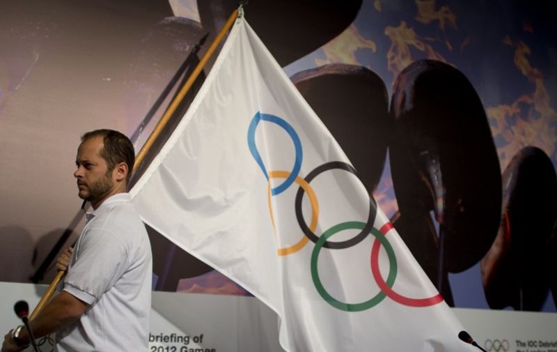 An employee carries the Olympic flag before the Intenational Olympic Commitee (IOC) debriefing of the London 2012 Olympic Games for the foreing press in Barra de Tijuca, Rio de Janeiro, Brazil on November 21, 2012.  AFP PHOTO/Christophe Simon