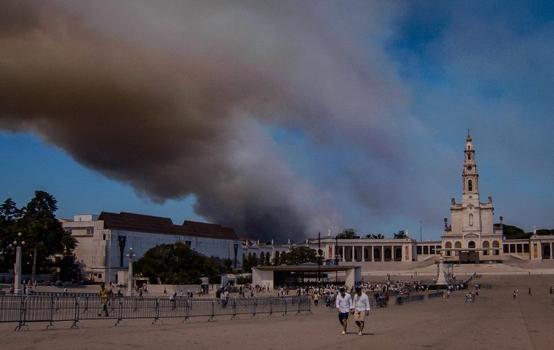 A column of smoke billows above the Sanctuary of Our Lady of Fatima, after a wildfire broke out in Fatima on August 5, 2023. A wildfire broke out as around 200,000 pilgrims flooded the shrine of Fatima in Portugal to attend a service held by Pope Francis at one of Catholicism's most revered sites devoted to the Virgin Mary. (Photo by CARLOS COSTA / AFP)