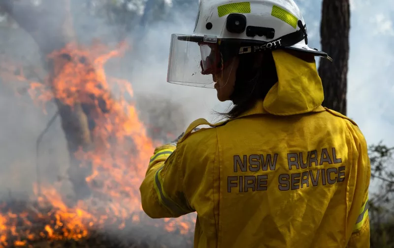 This picture taken on July 15, 2023 shows a volunteer firefighter monitoring a hazard reduction burn in north Sydney. Australian firefighters are preparing what they predict will be the fiercest fire season since the monster "Black Summer" blazes of 2019-2020. However, some warn that these brave volunteers may one day be unable to cope if global warming leads to raging fires, storms, and floods of ever-increasing intensity. (Photo by Aston Brown / AFP) / To go with AFP story Australia-environment-climate-fire,FOCUS by Sharon Marris and Andrew Leeson