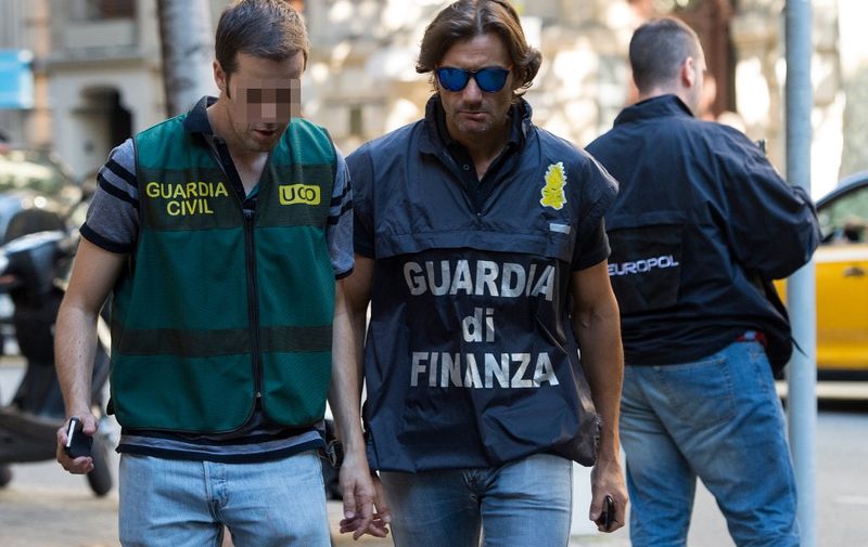 An Italian Guardia di Finanza officer (C) walks with a Guardia Civil officer (L) beside a Europol member as they take part in a search at a Restaurant in Barcelona during an international police operation against Italian Mafia on July 5, 2017. - At least 10 people were detained in Barcelona today as part of a Europe-wide operation, including Italy and Germany, against members of Italy's Camorra crime syndicate, a Spanish police spokesman said. (Photo by Josep LAGO / AFP)