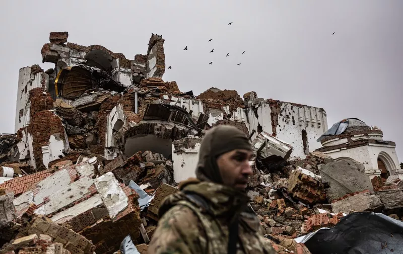 Caesar, 50-year-old, a Russian who joined the Freedom of Russia Legion to fight on the side of Ukraine, stands in front of a destroyed monastery in Dolyna, eastern Ukraine on December 26, 2022. - Freedom of Russia Legion is a Foreign volunteer legion formed in March 2022 with defectors from the Russian Armed Forces, Russian and Belarusian volunteers. (Photo by Sameer Al-DOUMY / AFP)