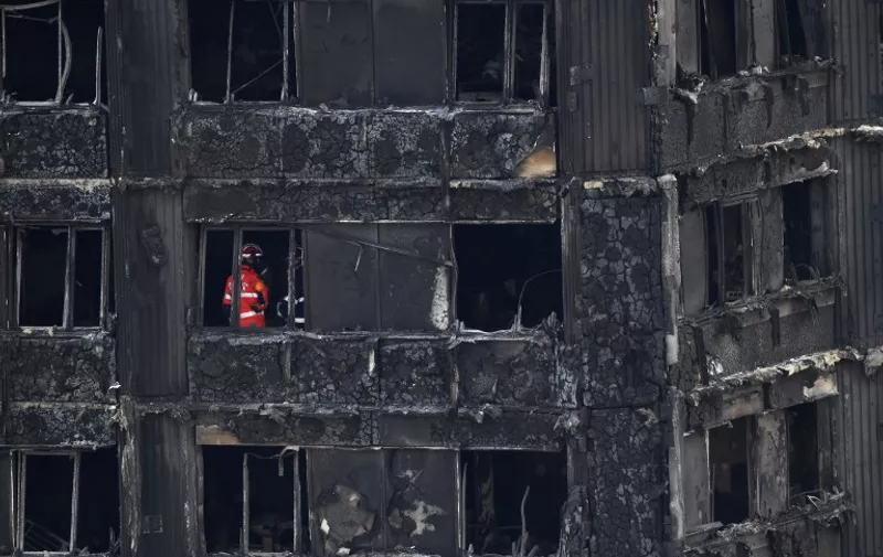 Emergency workers and police inspect inside the remains of Grenfell Tower, a residential tower block in west London which was gutted by fire, on June 16, 2017.
Dozens of people are feared dead in the London tower block fire as emergency workers continued searching for bodies in the high-rise on Friday, warning they may never be able to identify some of the victims. / AFP PHOTO / Chris J Ratcliffe
