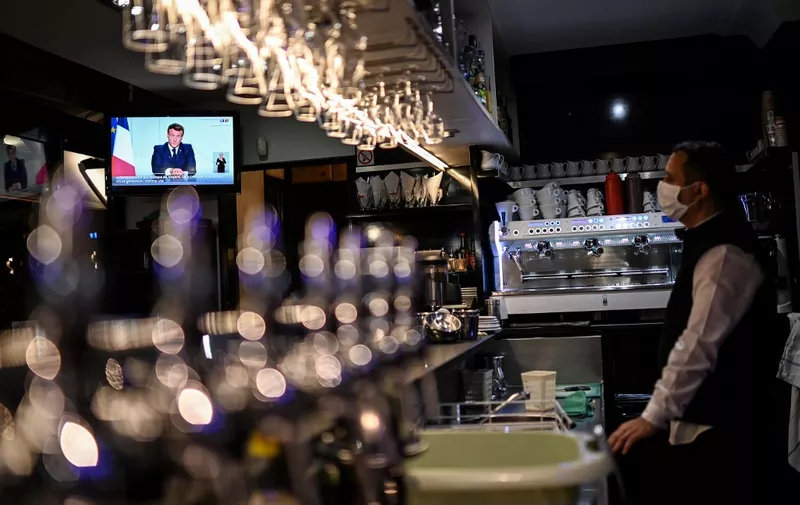 French President Emmanuel Macron is seen on a TV screen in a cafe in Marseille, southern France, on October 28, 2020, as he delivers an evening televised address to the nation, to announce new measures aimed curbing the spread of the Covid-19 pandemic, caused by the novel coronavirus. - France was preparing on October 28 for tough new restrictions to halt a flare-up in Covid-19 cases that has alarmed doctors, with a second lockdown widely mooted as hospitals battle an influx of patients. (Photo by CHRISTOPHE SIMON / AFP)