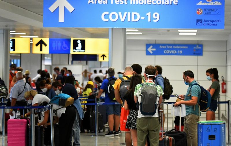 Passengers queue to be screened for Covid-19 at a testing station set up at Fiumicino airport, near Rome, on August 16, 2020. - Italy has introduced mandatory Covid-19 (novel coronavirus) testing for anyone arriving from Croatia, Greece, Spain and Malta and banned all visitors from Colombia, in a bid to rein in new infections. (Photo by Alberto PIZZOLI / AFP)