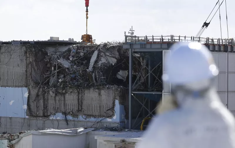 A member of the media, wearing a protective suit and a mask, looks at the No. 3 reactor building during a press tour at Tokyo Electric Power Co's (TEPCO) tsunami-crippled Fukushima Daiichi nuclear power plant in the town of Okuma, Fukushima prefecture on February 10, 2016.  The media tour of the facilities came as Japan readied to mark the fifth anniversary of the March 11, 2011 earthquake and tsunami that caused disastrous meltdowns at the Fukushima nuclear power plant.     AFP PHOTO / POOL / Toru HANAI / AFP / POOL / TORU HANAI