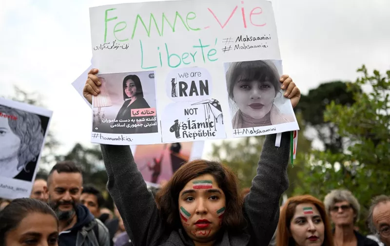 A protester holds a placard during a demonstration in support of Kurdish Iranian woman Mahsa Amini during a protest on October 3, 2022 in Nantes, weetern France, following her death in Iran. - Amini, 22, died in custody on September 16, 2022, three days after her arrest by the notorious morality police in Tehran for allegedly breaching the Islamic republic's strict dress code for women. in Nantes, western France on September 29, 2022. (Photo by Damien Meyer / AFP)