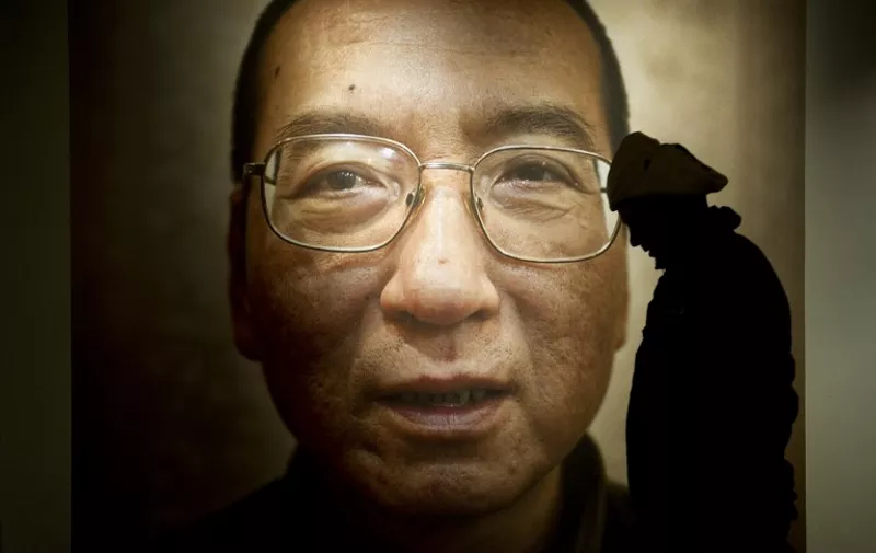 A man walks in front of a poster of Chinese dissident and peace prize laureate Liu Xiaobo at an exhibition at the Nobel Peace Center in Oslo, December 9, 2010. With the guest of honour stuck in a Chinese prison, this year's Nobel Peace Prize ceremony will centre around an empty chair, as its celebration of dissident Liu Xiaobo continues to split the global community and infuriate Beijing. The Norwegian Nobel Committee head said he was surprised at the level of international support for jailed Chinese dissident and peace prize laureate Liu Xiaobo despite pressure from Beijing.  AFP PHOTO/ODD ANDERSEN / AFP PHOTO / ODD ANDERSEN