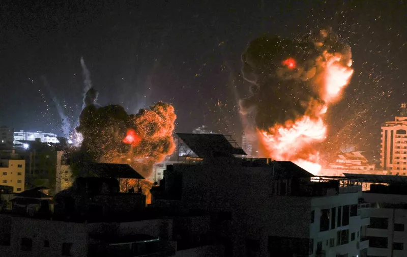 Explosions light-up the night sky above buildings in Gaza City as Israeli forces shell the Palestinian enclave, early on May 18, 2021. - Israeli jets kept up a barrage of air strikes against the Palestinian enclave of Gaza as a week of violence that has killed more than 200 people pushed world leaders to step up mediation. (Photo by MAHMUD HAMS / AFP)