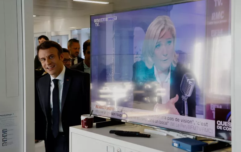 French President and liberal party La Republique en Marche (LREM) candidate for re-election Emmanuel Macron visits France Inter's office, next to a TV screen displaying French far-right party Rassemblement National (RN) presidential candidate Marine Le Pen (R), after the France Inter 7/9 radio broadcast at the Maison de la Radio in Paris, on April 4, 2022. - French voters head to the polls for a two-round presidential election on April 10 and 24, 2022. (Photo by Ludovic MARIN / AFP)