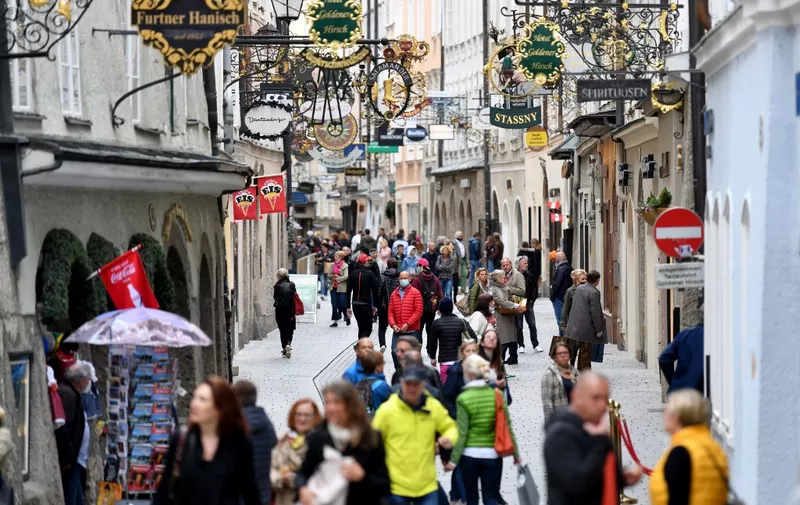 People walk in the shopping street 'Getreidegasse' in the old town in Salzburg, Austria on May 2, 2020. - Austrian citizens are allowed to leave the house for non-essential trips as it eases coronavirus lockdown measures, but said limits on gatherings and social distancing rules would remain in place. From May 2, 2020, shopping centres, hairdressers and all shops with more than 400 square metres of sales area are allowed to reopen, including the major electrical retailers, fashion chains, furniture stores and sports equipment retailers. (Photo by BARBARA GINDL / APA / AFP) / Austria OUT