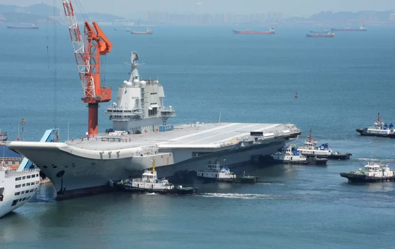 This photo taken on May 18, 2018 shows tugs guiding China's first domestically manufactured aircraft carrier, known as "Type 001A", as it returns to port in Dalian in China's northeastern Liaoning province after its first sea trial. China's first domestically manufactured aircraft carrier started sea trials on May 13, 2018 and returned to port in Dalian on May 18. (Photo by AFP) / China OUT