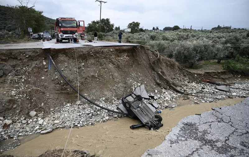 A picture taken on September 6, 2023 shows a car in the river bed after a road collapsed due to heavy floods in Kala Nera near the city of Volos, central Greece. (Photo by Sakis MITROLIDIS / AFP)