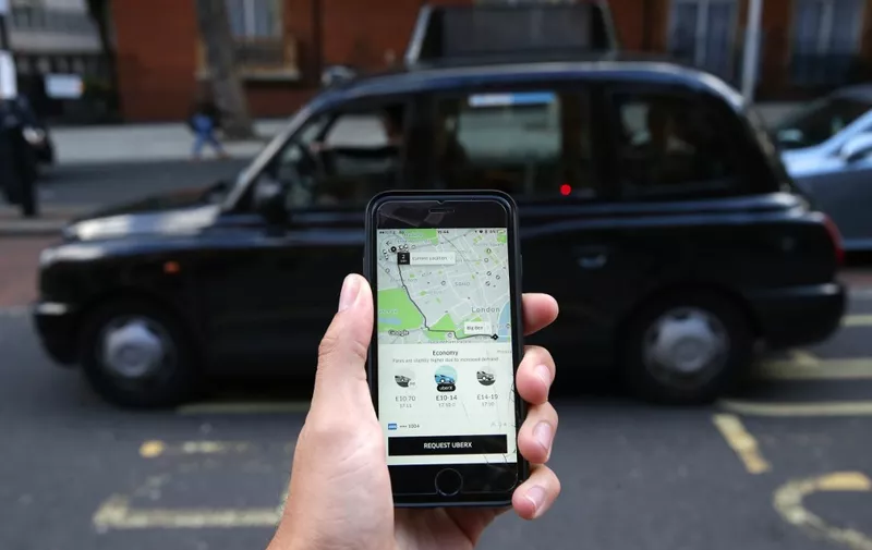 (FILES) In this file photo taken on September 22, 2017 A woman poses holding a smartphone showing the App for ride-sharing cab service Uber in London. - London's transport authority on November 25, 2019 refused to renew an operating licence for the ride-hailing giant Uber because of safety and security concerns. (Photo by Daniel LEAL-OLIVAS / AFP)