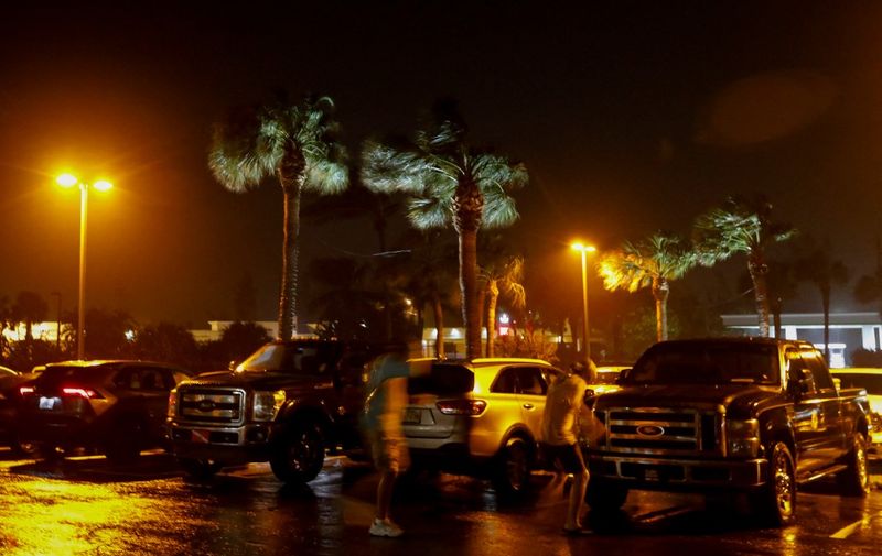 People fight the wind as they walk in a parking lot before Hurricane Nicole makes landfall in Jensen Beach, Florida on November 9, 2022. - Nicole, now a category 1 hurricane, is expected to make landfall over Florida's coast overnight. (Photo by Eva Marie UZCATEGUI / AFP)