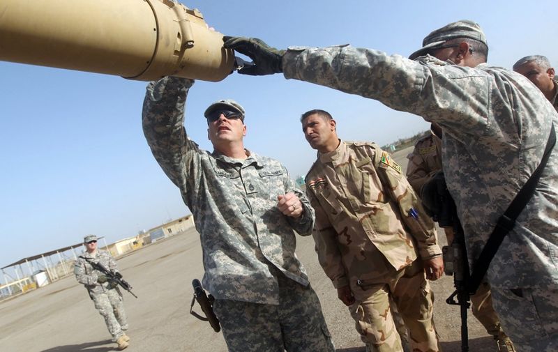 American and Iraqi military trainers shows Iraqi soldiers how to check the barrel of a tank at the Taji base complex, which hosts Iraqi and US troops and is located north of the capital Baghdad, on January 7, 2015. Taji is one of an eventual five sites from which the US and allied countries aim to train 5,000 Iraqi military personnel every six to eight weeks for combat against the Islamic State (IS) jihadist group. AFP/ PHOTO/AHMAD AL-RUBAYE (Photo by AHMAD AL-RUBAYE / AFP)
