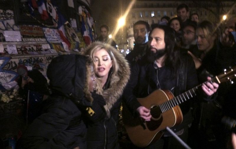 US singer Madonna (C) sings next to her guitarist Monte Pittman (C-R) and her son David Banda (L) on December 10, 2015 at the place de la Republique in Paris at a makeshift memorial in tribute to victims of November 13 terror attacks in Paris.
Singer Madonna made an emotional appeal following November 13 attacks in Paris that killed 130, shouting "We will not bend down to fear!" during a concert in the French capital. The star then moved to Place de la Republique, which has become an unofficial hub for mourners of the attacks, and sang a series of songs to a small crowd. / AFP / Jules Mahe