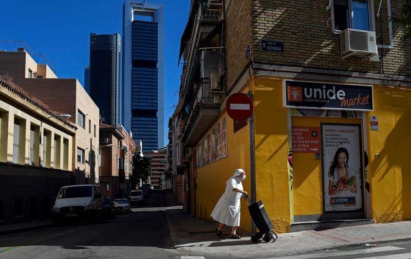 A nun wearing a facemask pushes a trolley in the outskirts of Madrid on August 19, 2020, with the Cuatro Torres bussiness area in the background. (Photo by OSCAR DEL POZO / AFP)